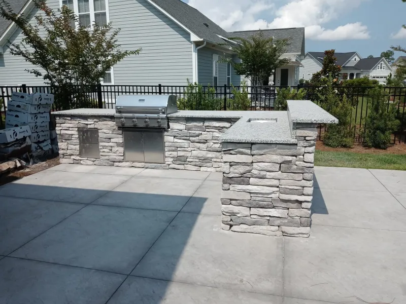 Stone outdoor grill station with concrete patio